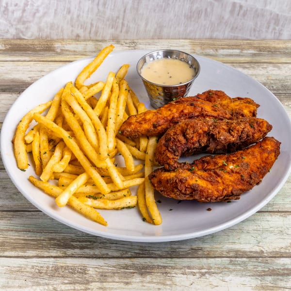 Crispy chicken tenders and seasoned french fries with a side of dipping sauce on a white plate.