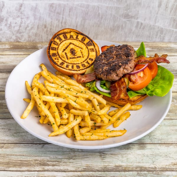 Bungalow Heights burger with bacon, lettuce, tomato, onion, and a side of seasoned fries.